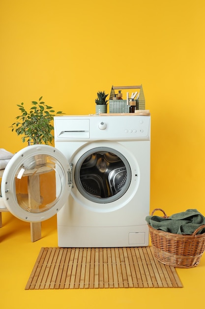 Concept de travaux ménagers avec machine à laver sur fond jaune