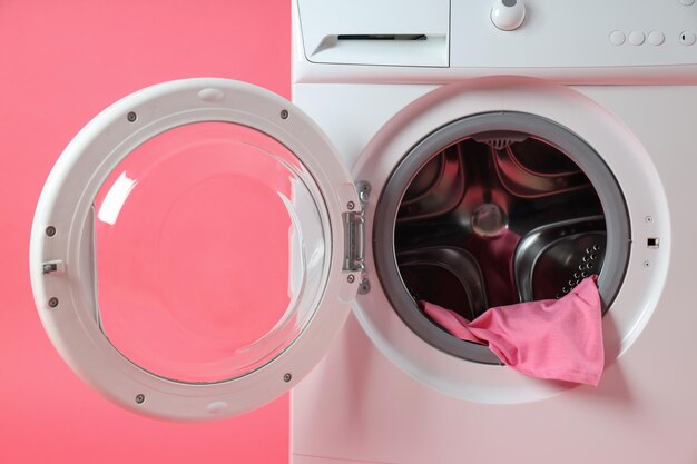 Concept de travaux ménagers avec machine à laver sur fond rose