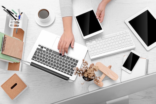 Concept d'utilisation de l'électronique Femme d'affaires travaille au bureau gros plan Ordinateur portable tablette tasse de café et d'autres choses sur la table Vue de dessus