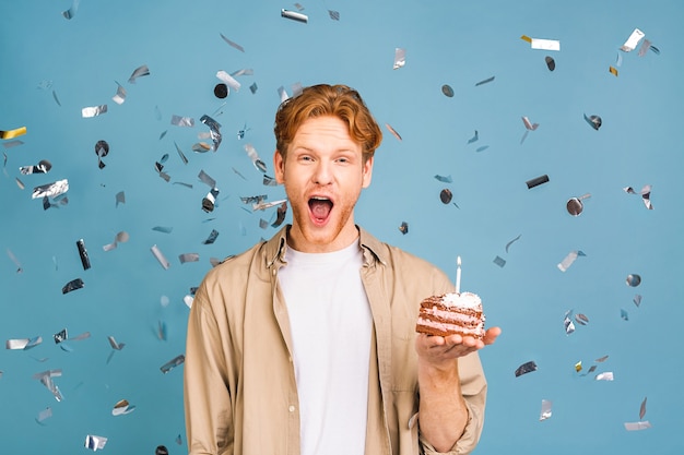 concept de vacances d'anniversaire ! portrait de joyeux jeune homme heureux tenant un gâteau d'anniversaire avec bougie