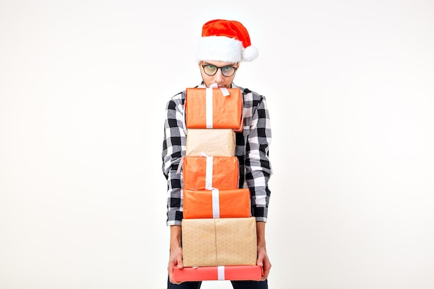 Concept de vacances et de cadeaux - Funny man in Christmas Santa hat holding de nombreux coffrets cadeaux sur fond blanc