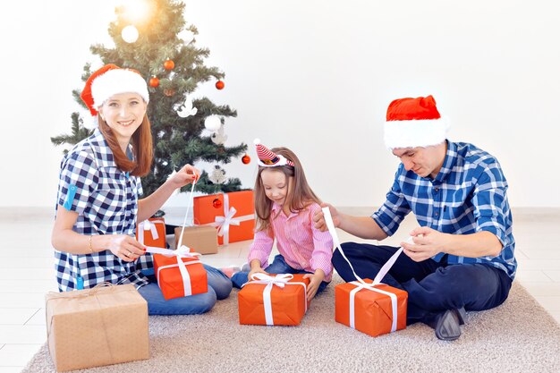 Concept de vacances et de cadeaux - Portrait d'une famille heureuse ouvrant des cadeaux au moment de Noël.