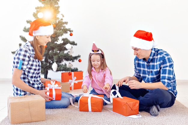 Concept de vacances et de cadeaux - Portrait d'une famille heureuse ouvrant des cadeaux au moment de Noël.