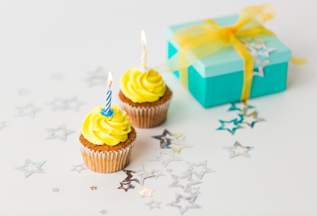 concept de vacances, célébration, salutation et fête - petits gâteaux d'anniversaire avec bougies allumées et cadeau