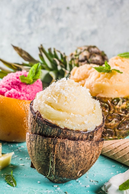 Concept de vacances d'été, définissez divers sorbets de crème glacée tropicale, jus congelés à l'ananas, au pamplemousse et à la noix de coco, béton bleu clair