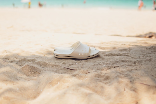 Concept de vacances d'été. Tongs sur une plage de sable de l'océan.