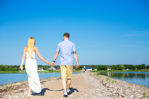 Concept de vacances d'été - vue arrière d'un couple heureux profitant de l'été sur la plage