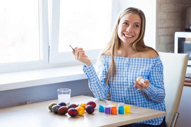 Concept de vacances, fait main et création - Heureuse jeune femme s'appuie sur l'oeuf de Pâques.