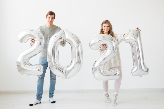 Concept de vacances, de fête et de fête - Un couple d'amoureux heureux tient des ballons en argent 2021