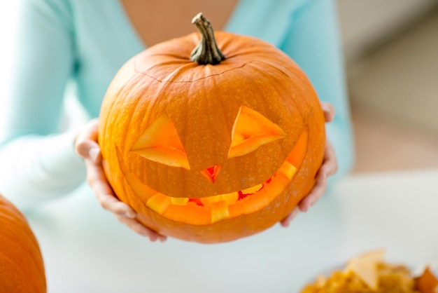 Concept de vacances, halloween, décoration et personnes - gros plan de femme avec des citrouilles à la maison