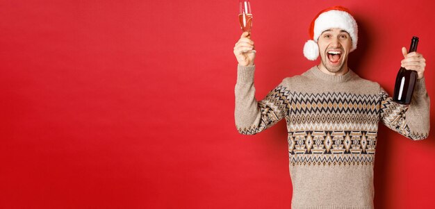 Concept de vacances d'hiver noël et célébration excité beau mec en pull et bonnet de noel e