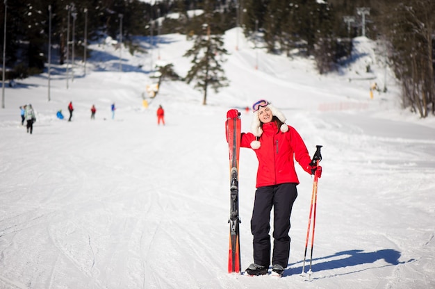 Concept de vacances d'hiver et de sport avec une femme d'aventure avec des skis dans ses mains au pied de la montagne.
