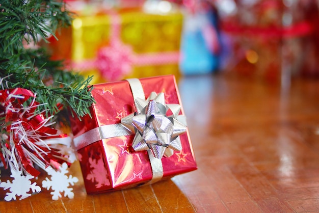Concept de vacances de Noël, une boîte cadeau rouge avec arbre de Noël sur le plancher en bois.