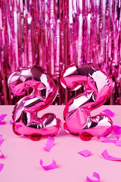 Concept de vacances et de la nouvelle année. 2022 ballons de papier d'aluminium rose et de confettis