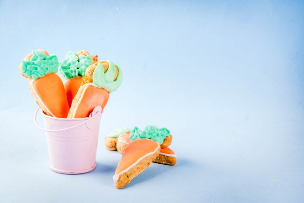 Concept de vacances de Pâques, biscuits sucrés en forme de carottes, fond bleu clair copie espace vue de dessus, fond de carte de voeux