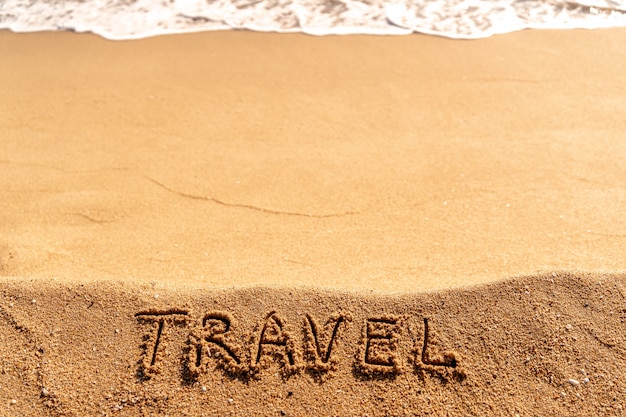 Concept de vacances sur la plage. Voyage de mot écrit sur le sable près de la mer.