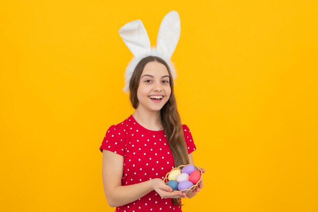 Concept de vacances pour enfants de Pâques Heureuse petite adolescente souriante avec des oreilles de lapin tenant des oeufs de Pâques peints