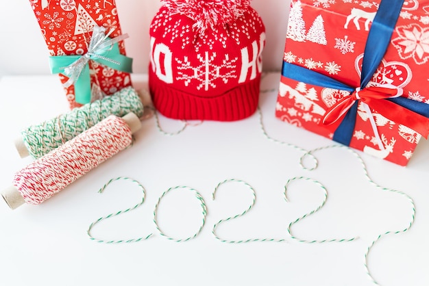 Concept de vacances pour Noël et nouvel an 2022. Disposition de divers attributs de Noël - chapeau, chaussette, fils rayés pour l'emballage.