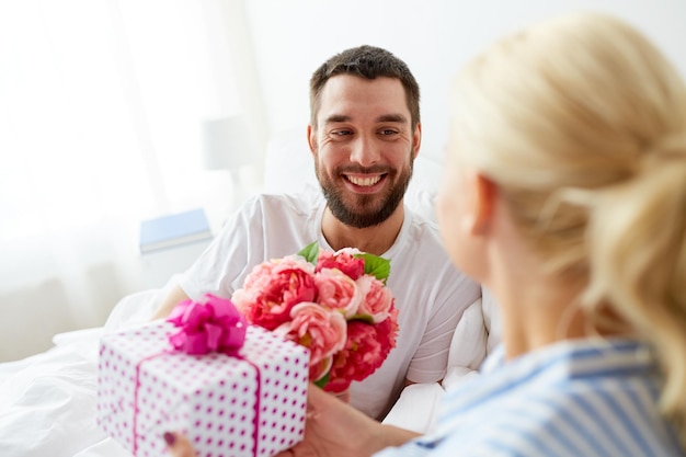 concept de vacances, de romance et de personnes - couple heureux avec boîte-cadeau au lit à la maison