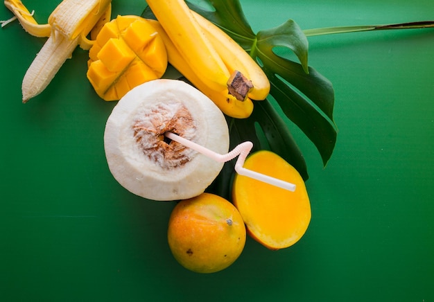 concept de vacances sous les tropiques mangue noix de coco et bananes sur fond vert avec place pour