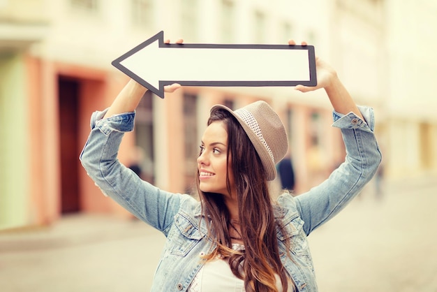 concept de vacances et de tourisme - belle fille montrant la direction avec une flèche dans la ville