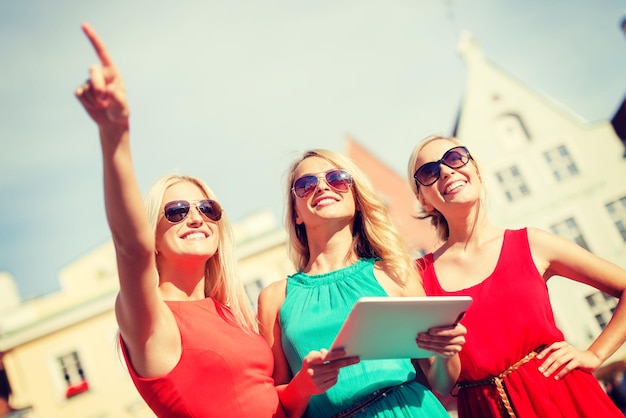 concept de vacances et de tourisme - belles filles blondes à la recherche d'un tablet pc dans la ville