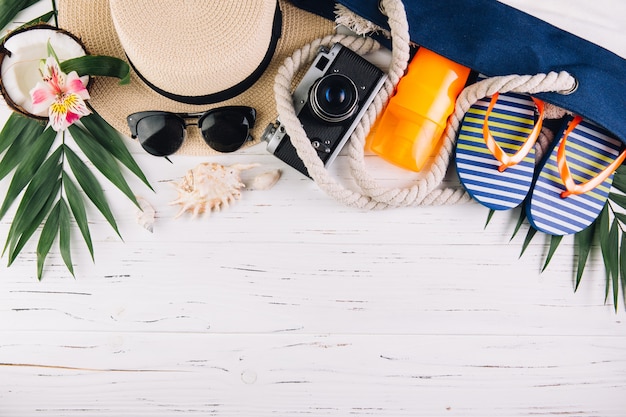 Concept de vacances de vacances d&#39;été. Sac de plage et accessoires sur une table en bois blanche. Vue de dessus et pose à plat