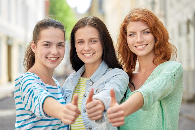 concept de vacances, de week-end, de loisirs et d'amitié - souriantes jeunes femmes ou adolescentes heureuses montrant les pouces vers le haut dans la rue de la ville