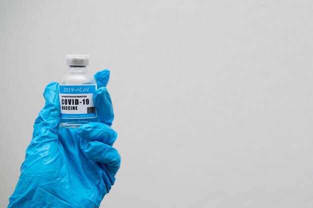 Concept de vaccin contre le coronavirus dans la main du pot de vaccin bleu du médecin