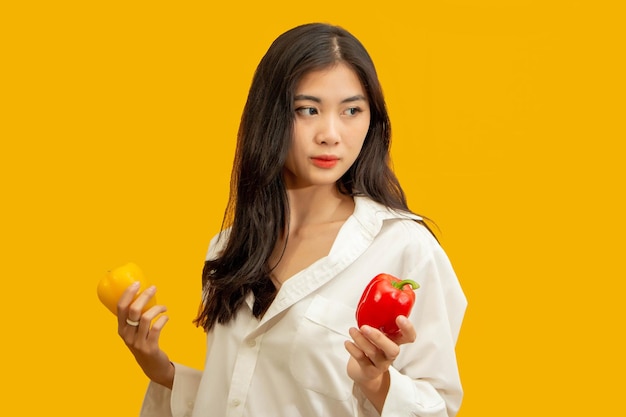 Concept végétarien Healthy woman holding poivron coloré sur fond jaune isolé