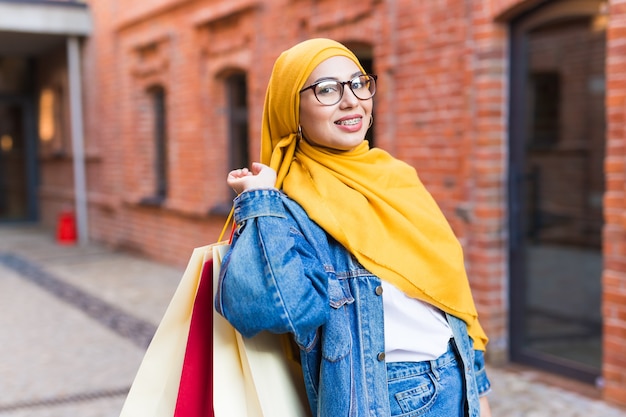 Concept de vente et d'achat - Bonne fille musulmane arabe avec des sacs après le centre commercial