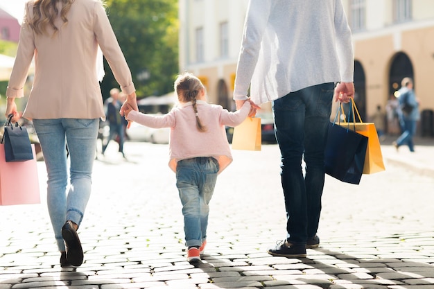 concept de vente, de consommation et de personnes - gros plan d'une famille heureuse avec un petit enfant et des sacs à provisions en ville