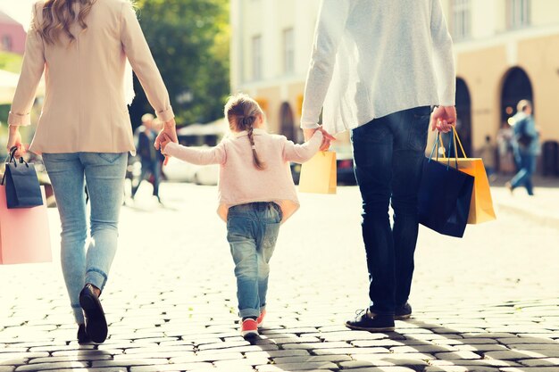 Photo concept de vente, de consommation et de personnes - gros plan d'une famille heureuse avec un petit enfant et des sacs à provisions en ville