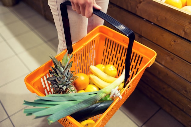 concept de vente, de shopping, de consommation et de personnes - gros plan d'une jeune femme avec un panier alimentaire sur le marché