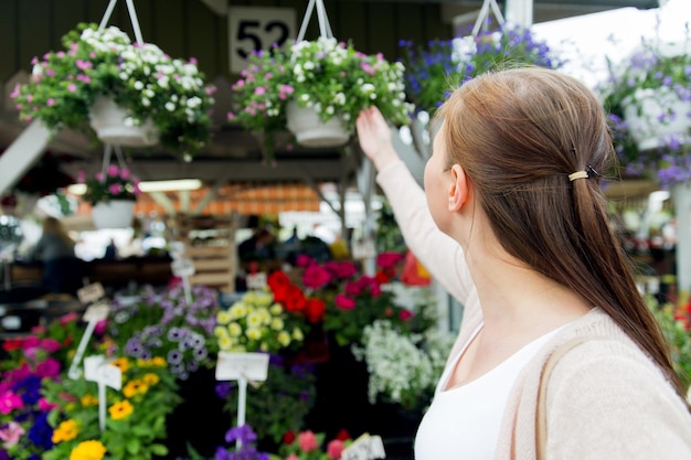 concept de vente, de shopping, de jardinage et de personnes - gros plan d'une femme choisissant des fleurs au marché de rue