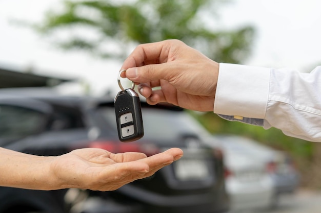 Concept de vente de voiture de vente de voiture Le concessionnaire donne les clés de la voiture au nouveau propriétaire ou au locataire avec un contrat d'assurance