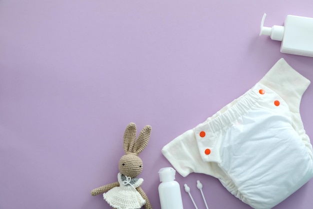 Concept de vêtements de bébé avec des couches réutilisables sur fond violet