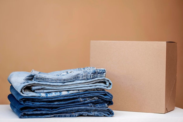 Concept de vêtements Une pile de jeans assortis et une boîte vide sur la table