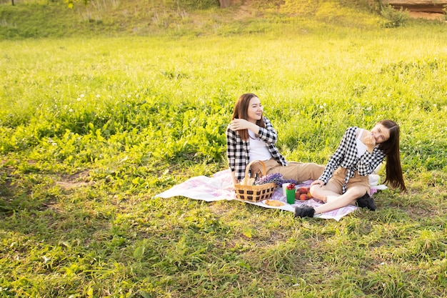 Photo concept de vie heureuse deux jolies filles de race blanche dans le parc sur l'herbe s'amuser passer un bon moment sont heureux