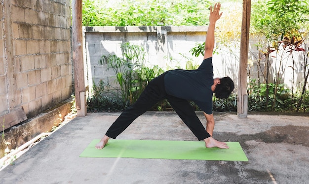 Concept de vie saine de l'homme pratiquant le yoga asana Triangle Pose travaillant sur des poses d'exercice