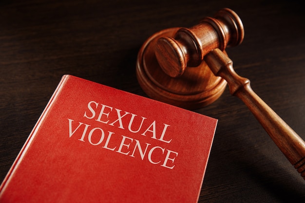 Concept de violence sexuelle. Marteau en bois sur le gros livre rouge.