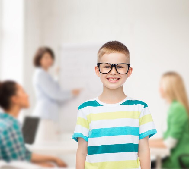 concept de vision, d'éducation et d'école - petit garçon souriant à lunettes sur fond blanc