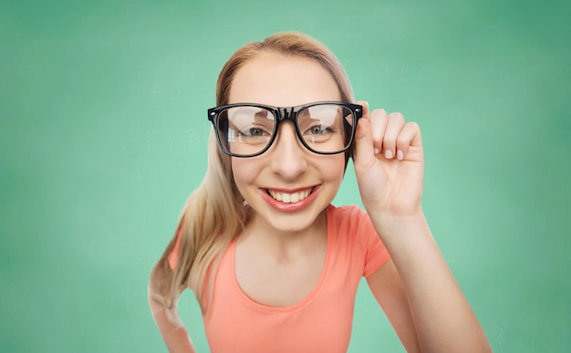 concept de vision, d'éducation et de personnes - jeune femme souriante heureuse ou lunettes d'adolescente sur fond de tableau de craie d'école verte