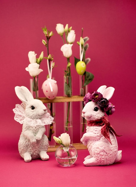 Concept de voeux de Pâques. Lapin de Pâques et fleurs de printemps blanches dans des vases sur fond rose.