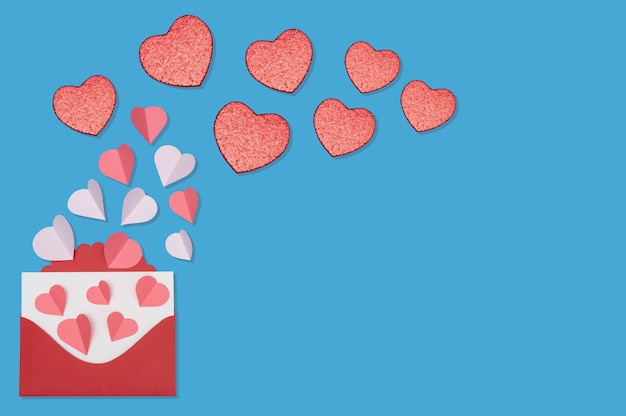 Concept de voeux Saint Valentin avec enveloppe et coeurs rouges sur fond bleu vue de dessus avec espace de copie pour le texte