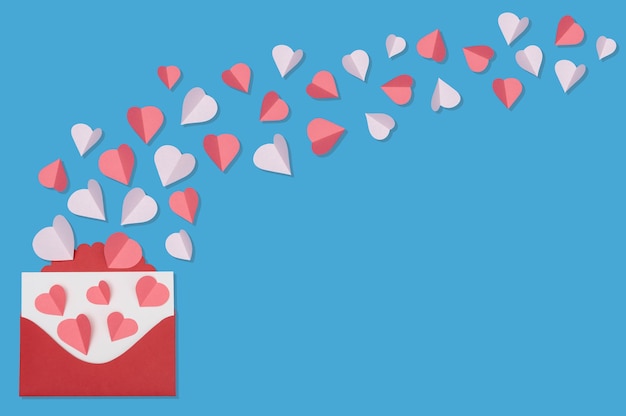 Photo concept de voeux saint valentin avec enveloppe et coeurs rouges sur fond bleu vue de dessus avec espace de copie pour le texte