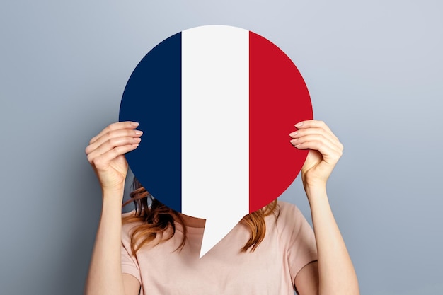 Photo concept de vote pour les élections en france une étudiante tient une affiche avec le drapeau de la france isolé sur fond de studio gris