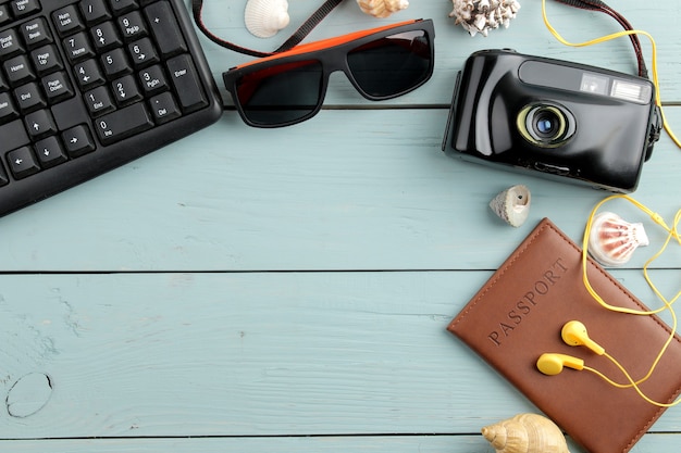 Concept de voyage Appareil photo, lunettes, passeport et coquilles sur une table en bois bleue. relaxation. vacances. vue de dessus. place libre.