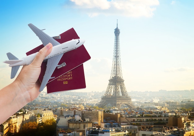 Concept de voyage en avion, main tenant des passeports avec avion, paysage urbain de Paris France en arrière-plan