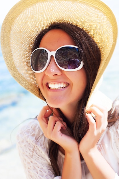 Concept de voyage - femme heureuse au chapeau sur la plage